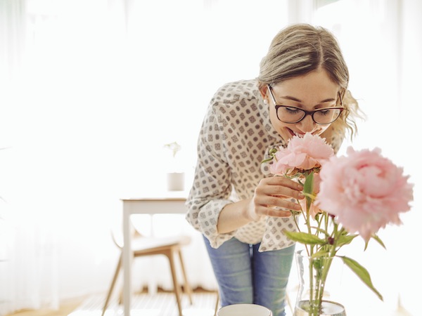 Ein Frau riecht erfreut an den Blumen, die ihr Partner ihr als Liebessignal geschenkt hat.